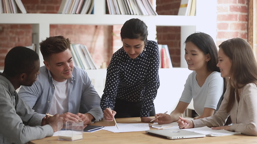 Focused young indian female architects designers students team leader draw with pencil plan new design project with multiethnic people group at office corporate meeting study work at table together | Shutterstock HD Video #1032911072