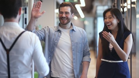Happy diverse colleagues greeting talking standing in office hall, smiling multiethnic staff professional people giving high five chatting laughing enjoy friendly conversation meeting in work space