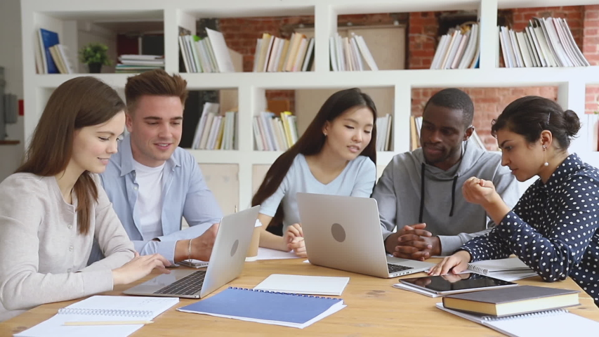 Focused diverse college university students team study together using laptop prepare for exam in library, multiethnic young people group talk looking at computer do online research project assignment Royalty-Free Stock Footage #1032911258