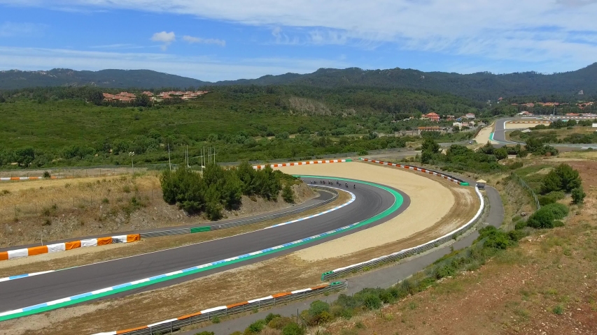 Aerial, descending, drone shot, of a group of cyclists, racing in a turn, on Estoril Circuit, at the 24h bike race, on a sunny day, near Lisbon, Portugal