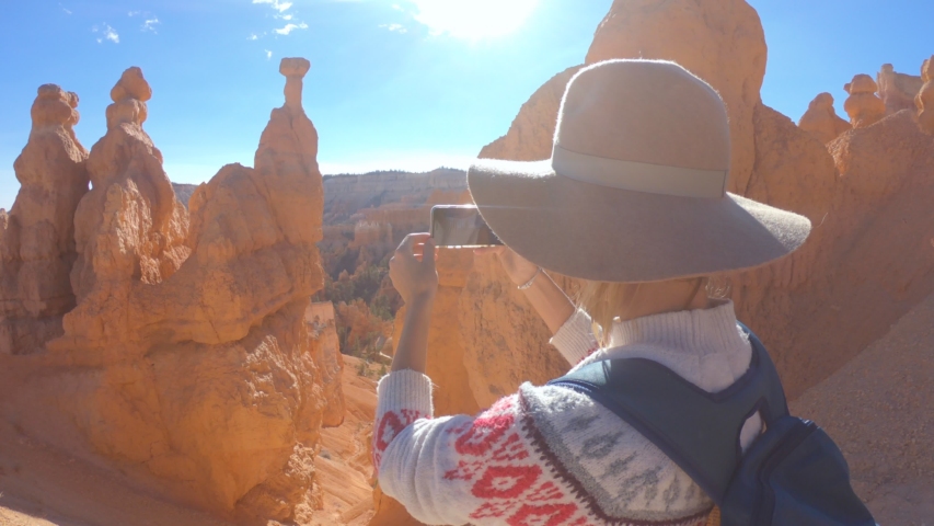 Young woman photographing Bryce Canyon using a smart phone