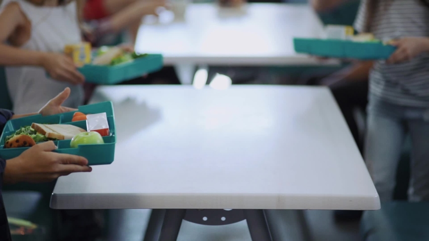 Cute elementary school children sitting by table eating their tasty snacks during lunch in cafeteria at school. | Shutterstock HD Video #1032918341