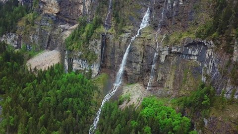 Aerial, drone shot, panning around a waterfall, on a cloudy day, at lake Oeschinensee, in Kandersteg, Bern, in the alps of Switzerland