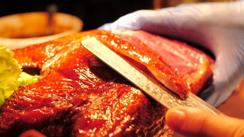 Close up Hands of Chef sliced duck skin from Roasted Whole Peking Duck. 