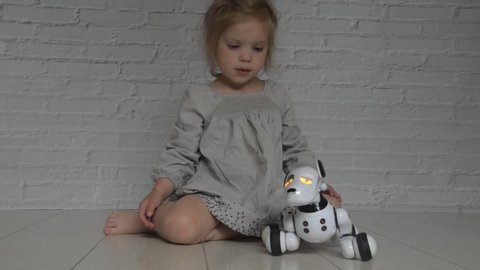 the baby girl playing takes care of dog robot