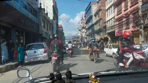 KATHMANDU, NEPAL - SEPTEMBER 2018: POV: Driving a car behind locals from Nepal riding motorcycles around Kathmandu. Cool view of speeding around the streets of Nepali capital city in an old car.