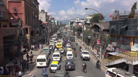 KATHMANDU, NEPAL - SEPTEMBER 2018: Countless vehicles get stuck on the road running through downtown Kathmandu. Breathtaking view from above of chaotic daytime traffic in the capital city of Nepal.