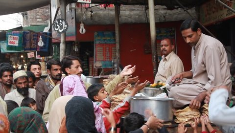 LAHORE - Circa OCTOBER, 2011: Men and children getting a free meal outside shrine of Ali Hajveri also known as Data Darbar in Lahore, Pakistan.