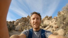 Young man taking selfie on mountain trail in the Californian desert in USA; hiker having fun enjoying nature and sport alone. 4K video shot with action camera 