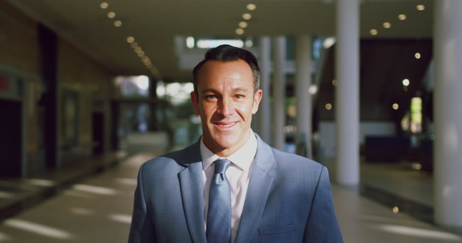 Front view of Caucasian Businessman looking at camera in a modern office. He is smiling 4k