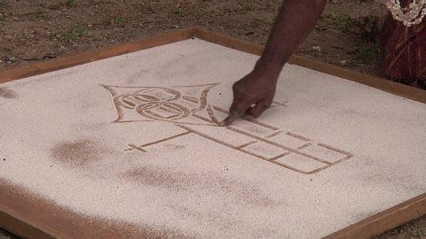 LOCKED OFF view of village elder doing sand drawing in Vanuatu on large board on the ground