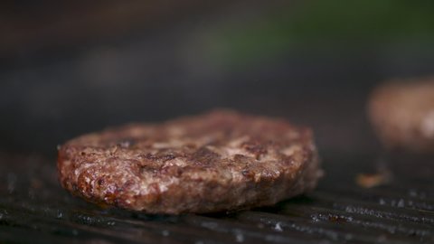 Close up, fresh, juicy hamburger patty cooking over a flaming barbecue grill