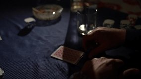 slow motion video of the hands of a man unfolding his cards while playing poker. A pair of 10 is visible in his hands