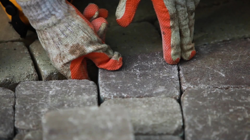 Stone pavement road construction workers. Cutting paving blocks for fitting the corners