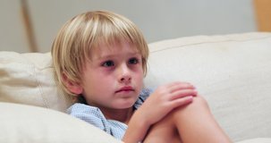 Child seated on sofa in the evening watching movie