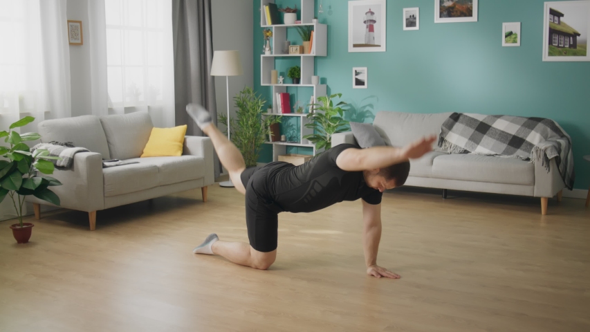 Young man is doing exercises on floor of modern apartment | Shutterstock HD Video #1032983132