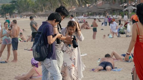 NhaTrang, Vietnam, November,14-2018. Cheerful girlfriends students on the beach. A group of Chinese tourists pose for the photographer. Women want to have a lot of beautiful photos from their vacation