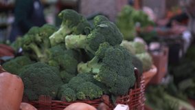 Fresh green Broccoli in a wooden basket Open market products Blurred people moving in background Handheld footage