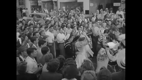 CIRCA 1945 - Soldiers and sailors dance the jitterbug with women on a crowded street, celebrating V-J Day.