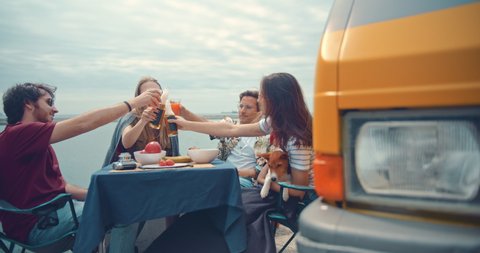 Multiracial happy friends enjoying camping vacation by camper van chilling near the sea making cheers and having fun, Adventure Summertime Holidays Concept, Slow Motion, Cinematic Shot