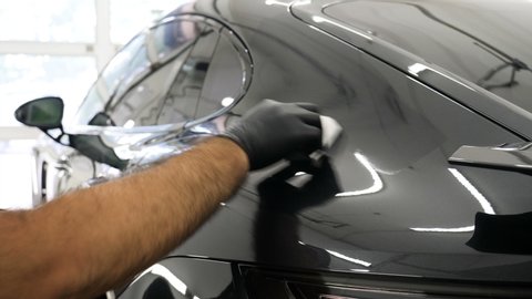 Staff wear Chemical protective clothing at work. Automobile industry. Car wash and coating business with ceramic coating.Spraying the varnish to the car. Concept of: Car protective, Service, Shine.