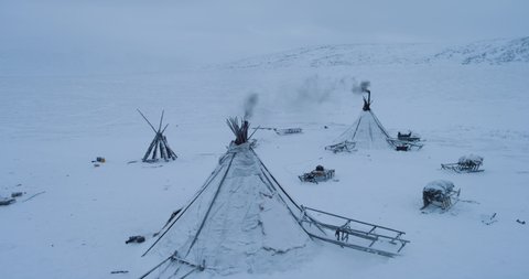 Drone capturing the yurts closeup in the evening in middle of Arctic , many sleigh outside the yurts.