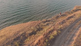 Aerial video of woman walks on the edge of a cliff. Flying over a cliff near the sea or ocean in Odessa 