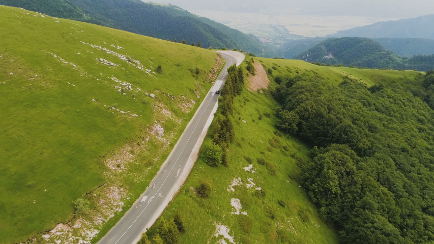 Top view of a car making a turn on a road situated on a steep mountain hill