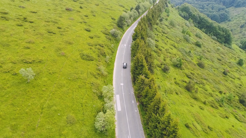 Top view of two vehicles calmly moving on a lonely highway up in the mountains.