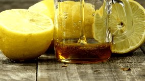 Closeup honey dropping in glass with lemon cut half on rustic wooden background.lemon with honey,freshness concept