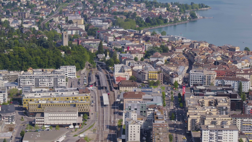 Aerial shot over Vevey train station, camera tilting up revealing Lake Leman and Montreux