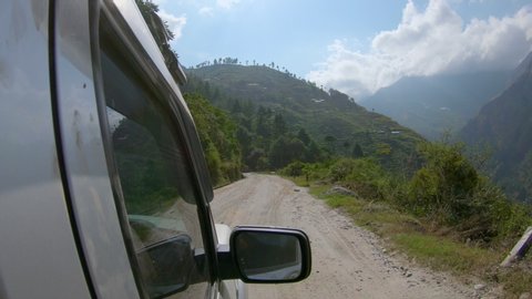POV Driving along a switchback road leading through the wilderness of Nepal as you travel to Tibet. Speeding in a 4x4 jeep along an unpaved road in the sunny Nepali countryside. Road trip across Nepal
