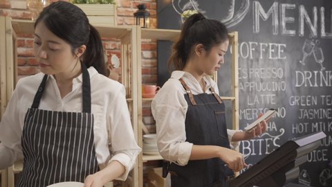 Small family restaurant owners checking monthly reports on tablet. two asian women wearing apron working as barista in cafe shop counter. elegant coworker staff helping waitress solve problem Video Stok