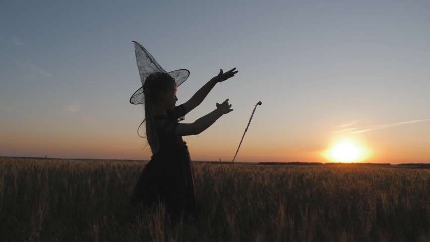 Silhouette of happy little girl dressed in a enchantress costume. The child presents herself as a sorceress, the concept of children