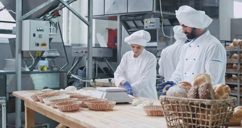 Baking industry three professional bakers working concentrated with dough they prepare for baking the bread , stylish dress code. shot on red epic