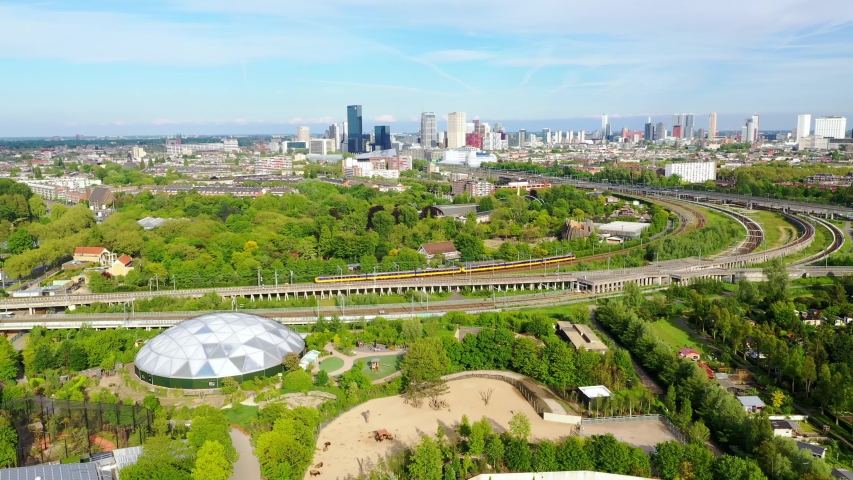 Aerial of an International high-speed rain leaving Rotterdam Centraal Station on elevated tracks as seen from blijdorp zoo and park, NS