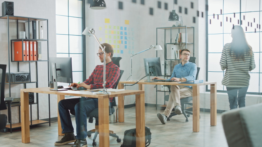 Young Professionals Working in Creative Agency in Loft Ofice. Female Colleague Comes to Chat to Coworker in Friendly Manner. Diverse Employees. Asking Manager for Advice.