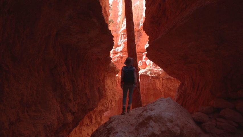 woman standing arms wide open inside narrow canyon. USA