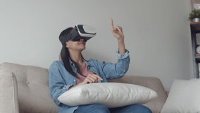 Attractive portrait young asian woman wearing VR headset at living room, playing game, watching movie. Wearing virtual reality headset.
