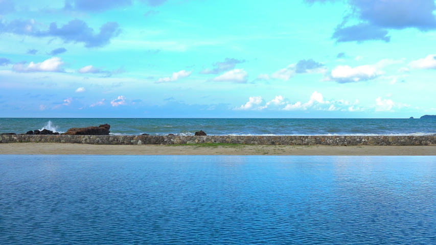 The view from the edge of a resort infinity? pool looking out over the beach and out to the ocean waves and horizon.