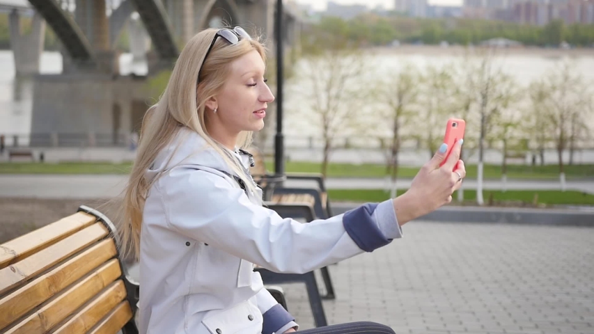 A happy excited young woman is impressing her friends on a webcam on her smartphone. A woman talks about local attractions during the trip. Slow motion.