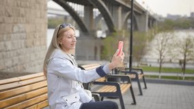 A happy excited young woman is impressing her friends on a webcam on her smartphone. A woman talks about local attractions during the trip. Slow motion.