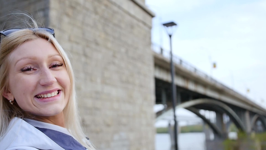 A happy excited young woman is impressing her friends on a webcam on her smartphone. A woman talks about local attractions during the trip. Slow motion.