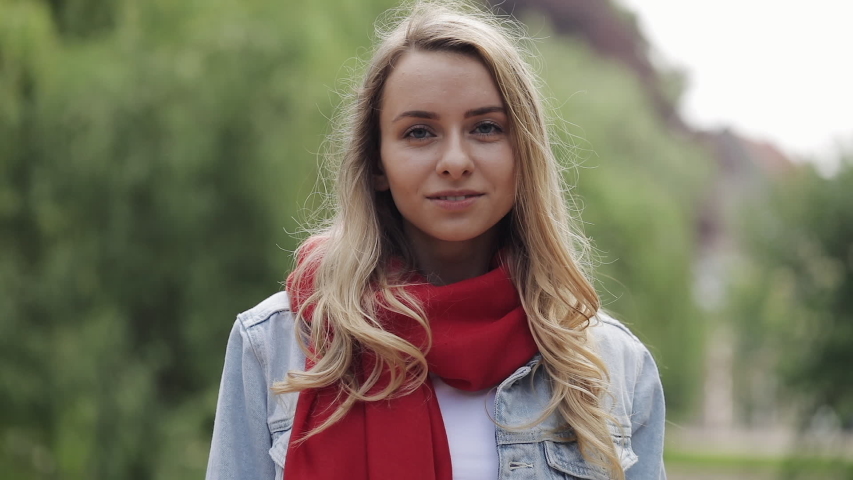 Portrait of young pretty woman laughing happy enjoying positive lifestyle wearing red scarf standing in the park. Close up, lifestyle.