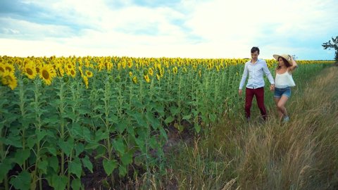 Young couple in love having fun on a date in a field of sunflowers.