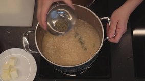 Adding dried oregano and basil into frying rice. Stirring constantly. Cooking risotto dish. Italian cuisine. Overhead shot