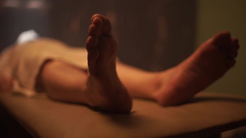 Dead male body laid out on an autopsy table comes back to life