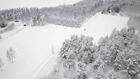 Aerial view of passenger car driving in countryside landscape in Finland with snowy surroundings.