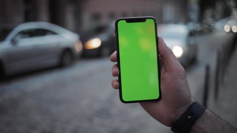 NEW YORK - April 19, 2019: At the evening hands using iPhone with vertical green screen smart mobile background 