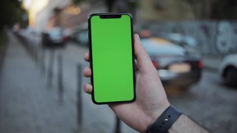 NEW YORK - April 19, 2019: Close up man hands using iphone with vertical green screen smart mobile background 